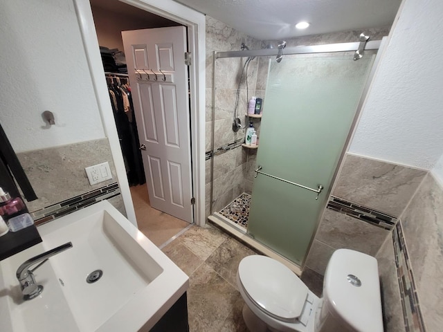 bathroom featuring tile walls, sink, an enclosed shower, and toilet