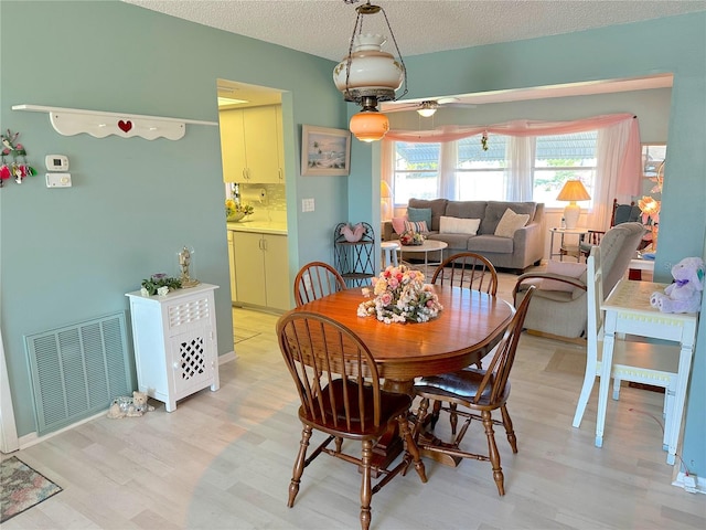 dining area featuring ceiling fan, a textured ceiling, and hardwood / wood-style flooring