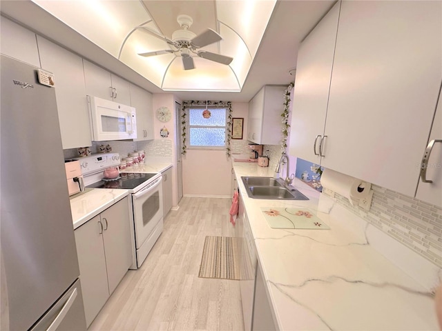 kitchen with decorative backsplash, white appliances, light hardwood / wood-style flooring, and sink