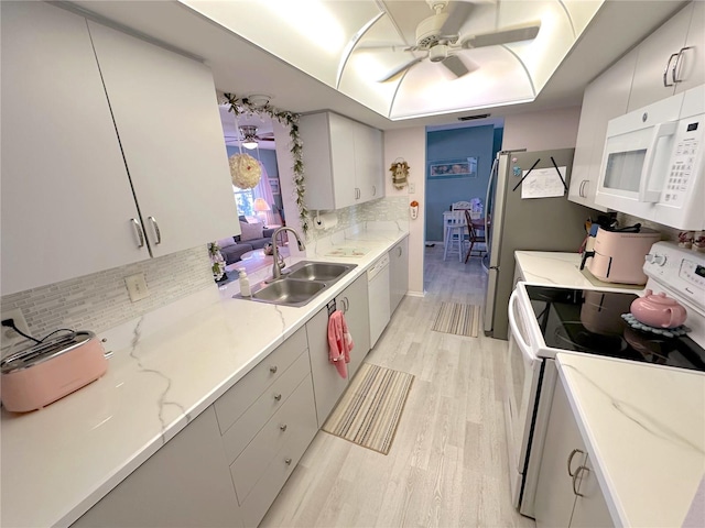 kitchen with backsplash, white appliances, ceiling fan, sink, and light hardwood / wood-style floors