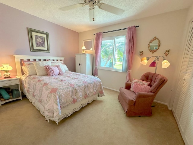 bedroom with a textured ceiling, a closet, light colored carpet, and ceiling fan