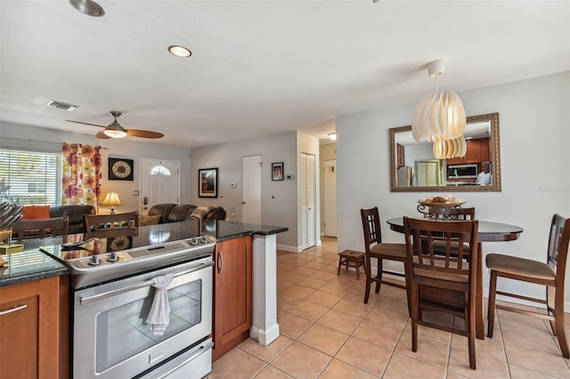 kitchen with brown cabinets, stainless steel appliances, dark countertops, visible vents, and open floor plan