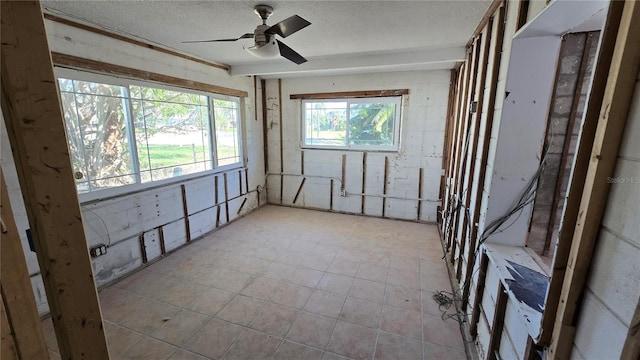 empty room with tile patterned floors, a ceiling fan, and a textured ceiling
