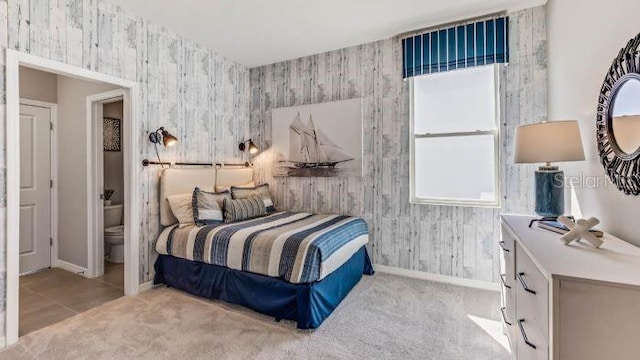 bedroom featuring ensuite bathroom and light colored carpet