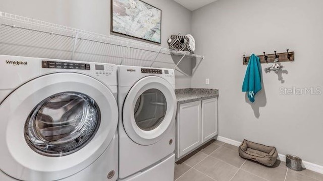 washroom with washer and clothes dryer, light tile patterned flooring, and cabinets