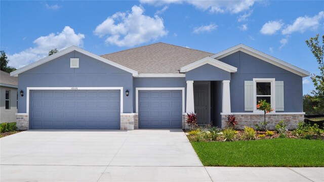 16026 10th Ave E, Bradenton, FL 34212 - view of front facade featuring stone siding, a garage, driveway, stucco siding, and a front lawn
