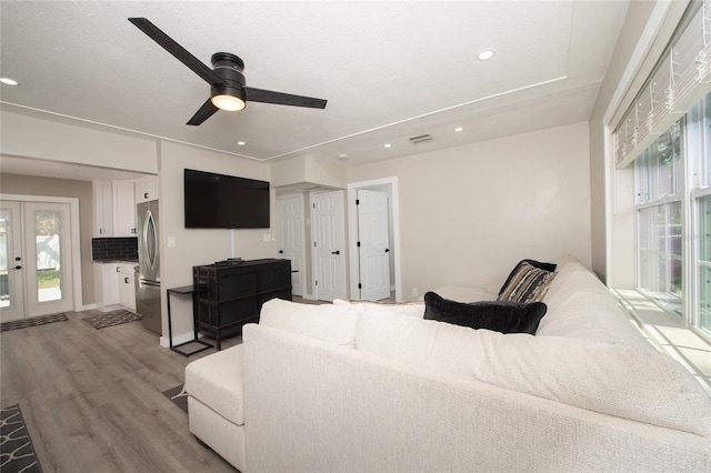 living room featuring ceiling fan, french doors, and light hardwood / wood-style floors