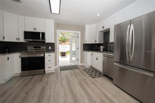 kitchen with light stone countertops, stainless steel appliances, light hardwood / wood-style floors, decorative backsplash, and white cabinets