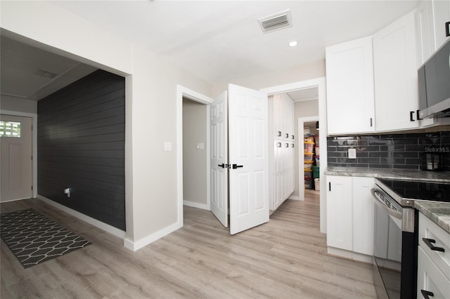 kitchen with white cabinets, decorative backsplash, stainless steel appliances, and light hardwood / wood-style flooring