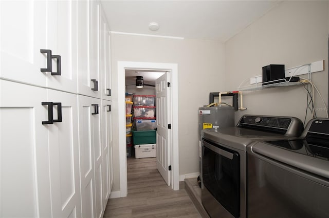 laundry area featuring water heater, light hardwood / wood-style flooring, cabinets, and independent washer and dryer