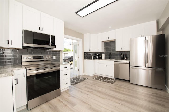 kitchen with white cabinets, light wood-type flooring, and stainless steel appliances