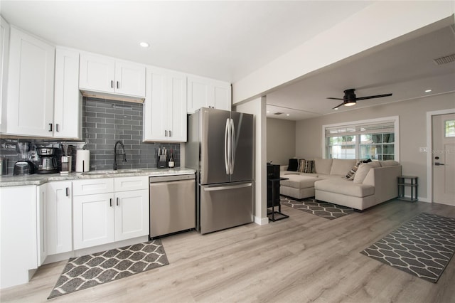 kitchen featuring sink, tasteful backsplash, light hardwood / wood-style floors, white cabinets, and appliances with stainless steel finishes