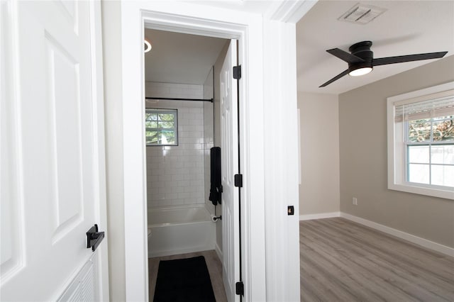 bathroom featuring hardwood / wood-style flooring, ceiling fan, and tiled shower / bath