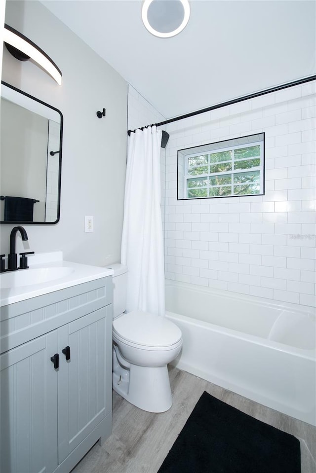 full bathroom featuring hardwood / wood-style floors, vanity, toilet, and shower / tub combo