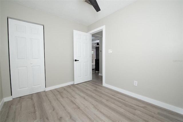 unfurnished bedroom featuring ceiling fan, a closet, and light wood-type flooring