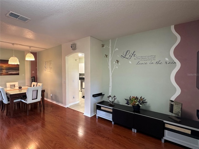 dining space with hardwood / wood-style floors and a textured ceiling