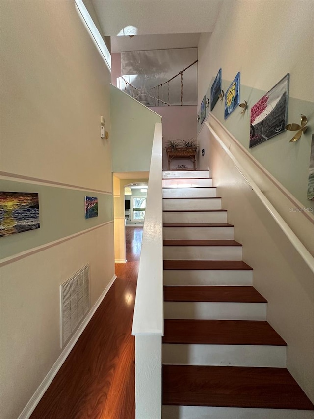 stairs with hardwood / wood-style flooring and a high ceiling