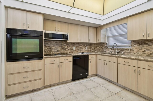 kitchen featuring light brown cabinets, light tile patterned flooring, black appliances, and sink