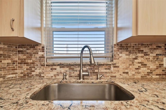 kitchen with tasteful backsplash, light stone counters, sink, and light brown cabinets