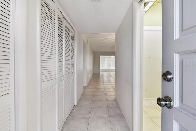 hallway featuring light tile patterned floors and a textured ceiling