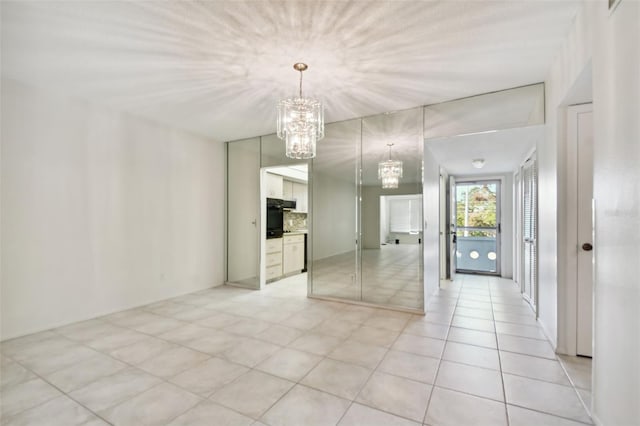 tiled spare room with a notable chandelier