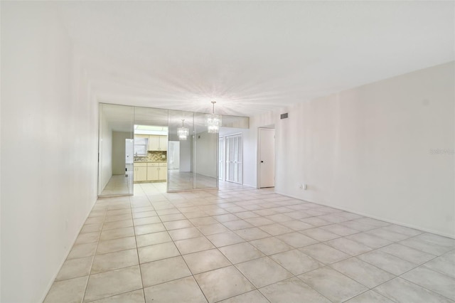 tiled empty room with a chandelier