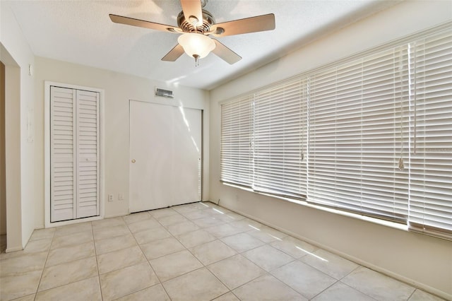 unfurnished bedroom with a textured ceiling, ceiling fan, and light tile patterned flooring