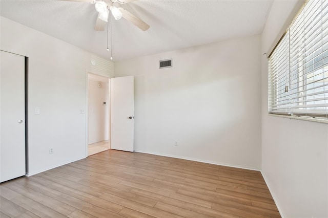 spare room with ceiling fan, light hardwood / wood-style floors, and a textured ceiling