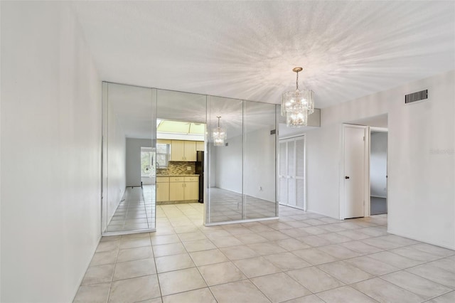 unfurnished room with a notable chandelier and light tile patterned flooring