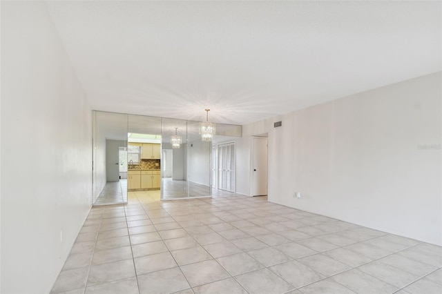 unfurnished room with light tile patterned floors and a notable chandelier