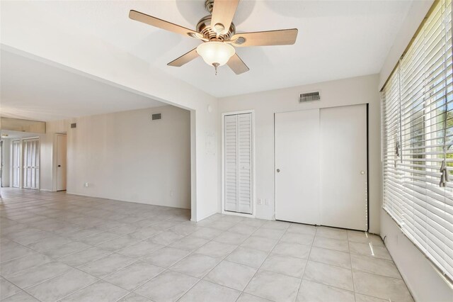 unfurnished bedroom featuring ceiling fan and two closets