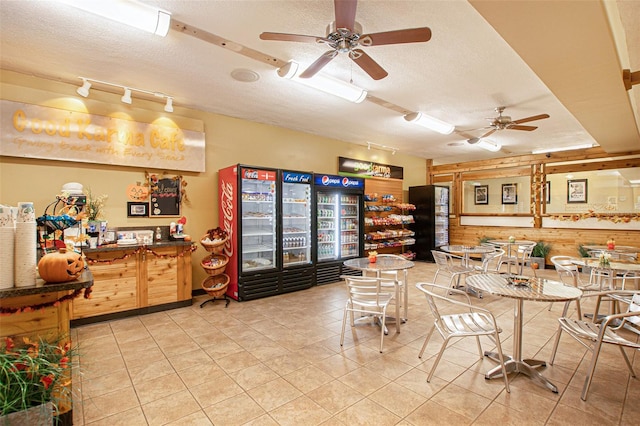 interior space with a textured ceiling, tile patterned floors, ceiling fan, and wooden walls