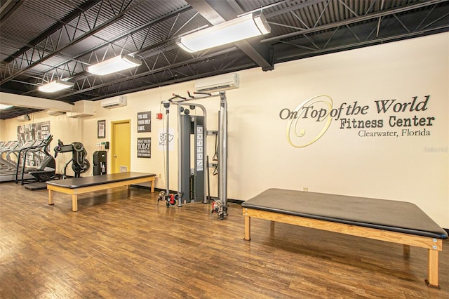 exercise room with wood-type flooring and a wall mounted air conditioner