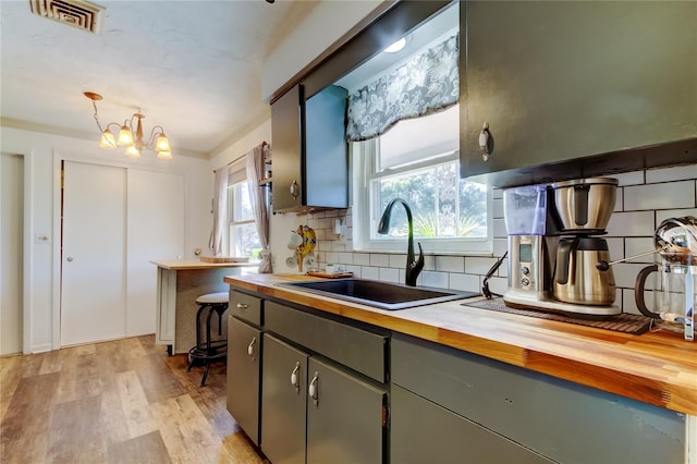 kitchen featuring butcher block countertops, a wealth of natural light, sink, and an inviting chandelier