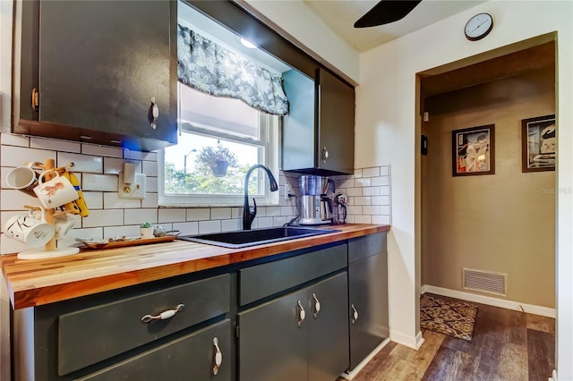 kitchen featuring butcher block countertops, dark hardwood / wood-style floors, sink, and tasteful backsplash