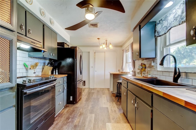 kitchen featuring sink, hanging light fixtures, black electric range, tasteful backsplash, and butcher block countertops