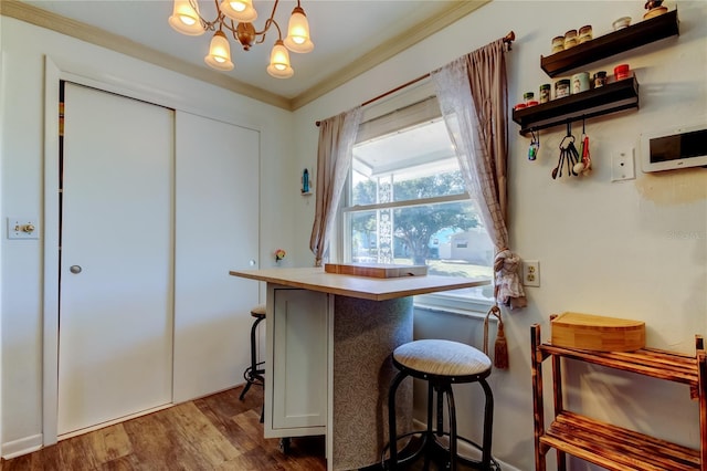 kitchen with a breakfast bar, dark wood-type flooring, ornamental molding, a notable chandelier, and kitchen peninsula