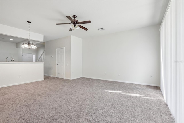 unfurnished living room featuring light carpet and ceiling fan with notable chandelier