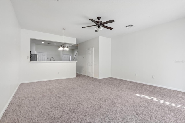 unfurnished living room featuring carpet and ceiling fan with notable chandelier