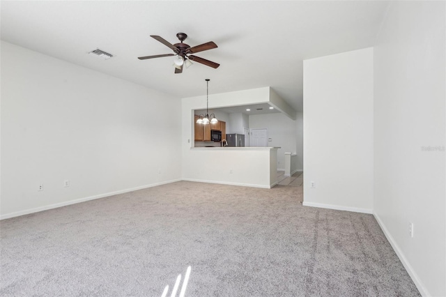 unfurnished living room featuring ceiling fan with notable chandelier and light colored carpet