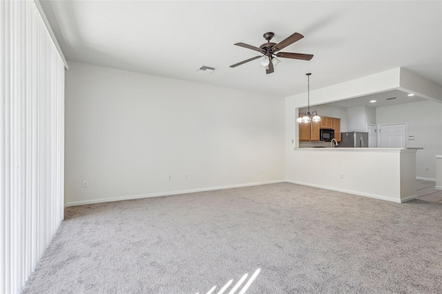 unfurnished living room featuring light carpet and ceiling fan with notable chandelier