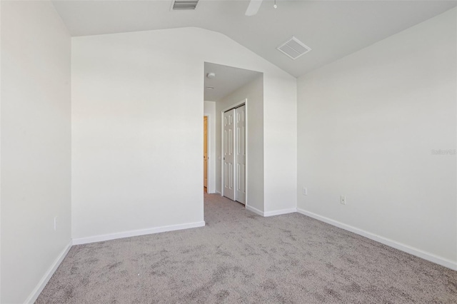 spare room featuring light colored carpet and lofted ceiling