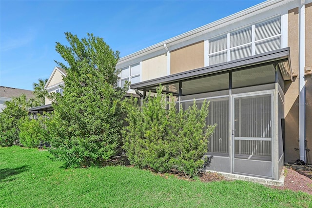 back of property featuring a lawn and a sunroom