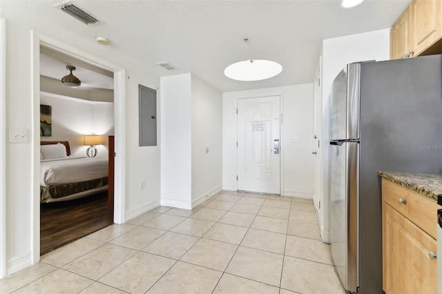 11605 Gulf Blvd Unit 507, Treasure Island, FL 33706 - kitchen with freestanding refrigerator, electric panel, light tile patterned floors, light brown cabinets, and baseboards