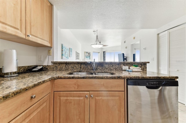 kitchen featuring dark stone counters, sink, stainless steel dishwasher, light tile patterned floors, and a textured ceiling