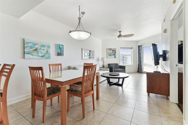 tiled dining room with ceiling fan and a textured ceiling