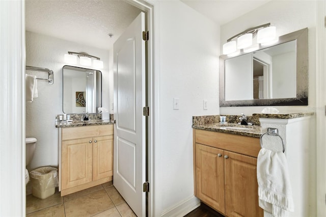 bathroom featuring tile patterned floors, vanity, toilet, and a textured ceiling