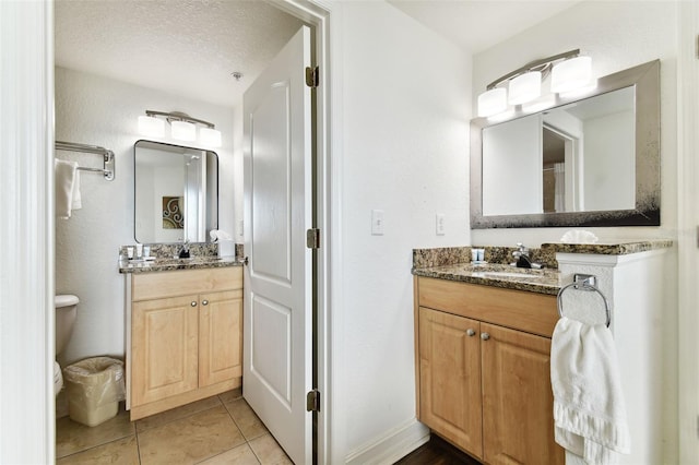 11605 Gulf Blvd Unit 507, Treasure Island, FL 33706 - full bath featuring two vanities, toilet, tile patterned flooring, baseboards, and a textured ceiling