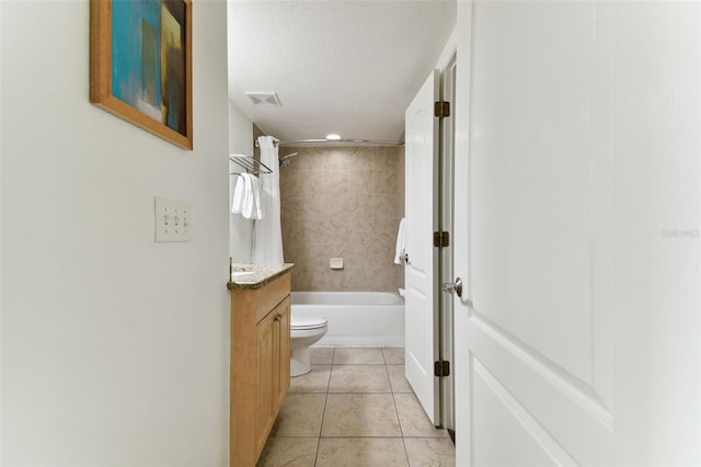 full bathroom featuring a textured ceiling, vanity, tiled shower / bath combo, tile patterned flooring, and toilet