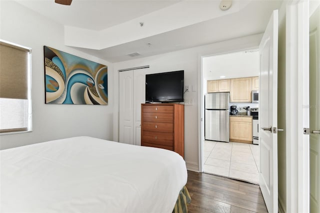 bedroom featuring stainless steel fridge, light wood-type flooring, and a closet